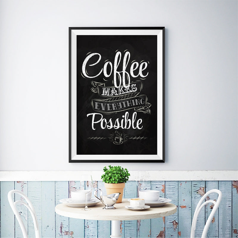 Print in a black frame hanging above a table set with teacups, saucers, and a small plant