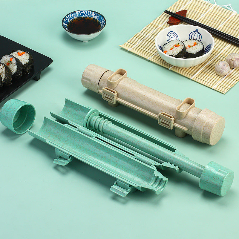 Sushi making tool taken apart in mint green and beige next to a plate of finished sushi rolls