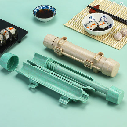 Sushi making tool taken apart in mint green and beige next to a plate of finished sushi rolls
