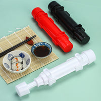 Red, black, and blue sushi making tools next to a bowl of finished sushi rolls and soy sauce