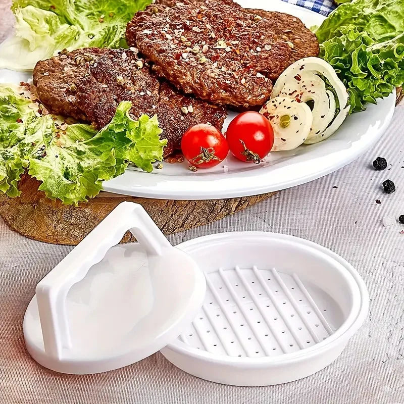 Burger press beside a plate of grilled meat patties with lettuce, tomato, and onion