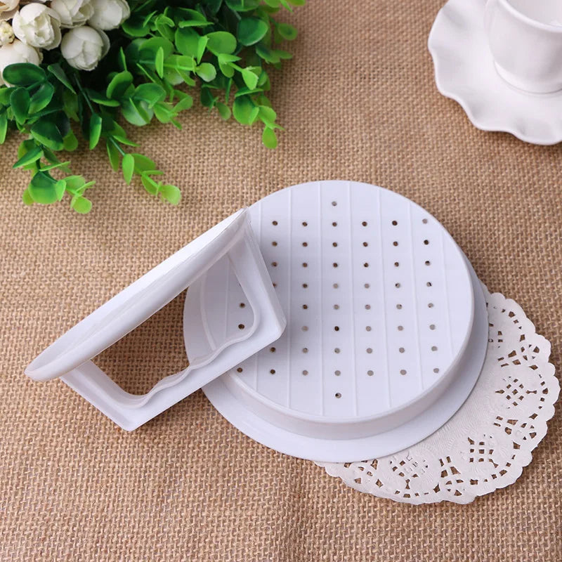 Disassembled plastic burger press showing the perforated patty disc and lift-handle lid