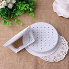 Disassembled plastic burger press showing the perforated patty disc and lift-handle lid