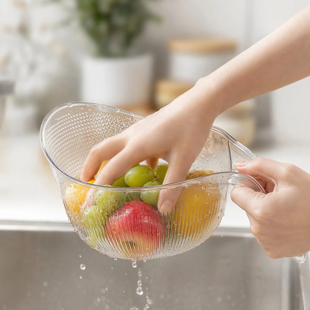 Close-up of hands rinsing mixed fruit in the colander bowl under running water