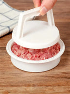 Close-up of a hand lifting the burger press lid to reveal ground meat pressed inside the mold