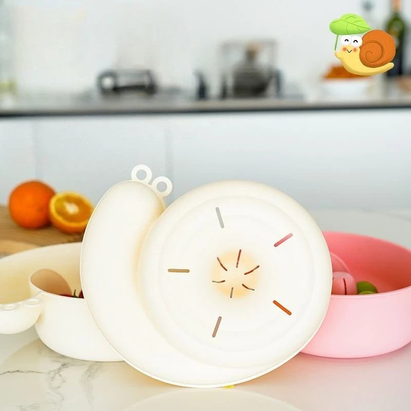 Cream snail-shaped basket on a kitchen counter next to oranges, with a pink basket of berries alongside