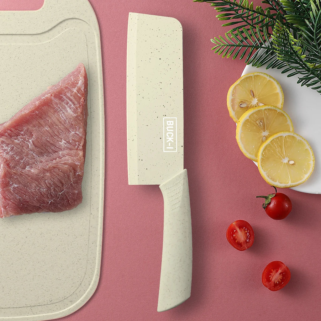 Cleaver-style knife next to raw meat on a cutting board with lemon slices and cherry tomatoes