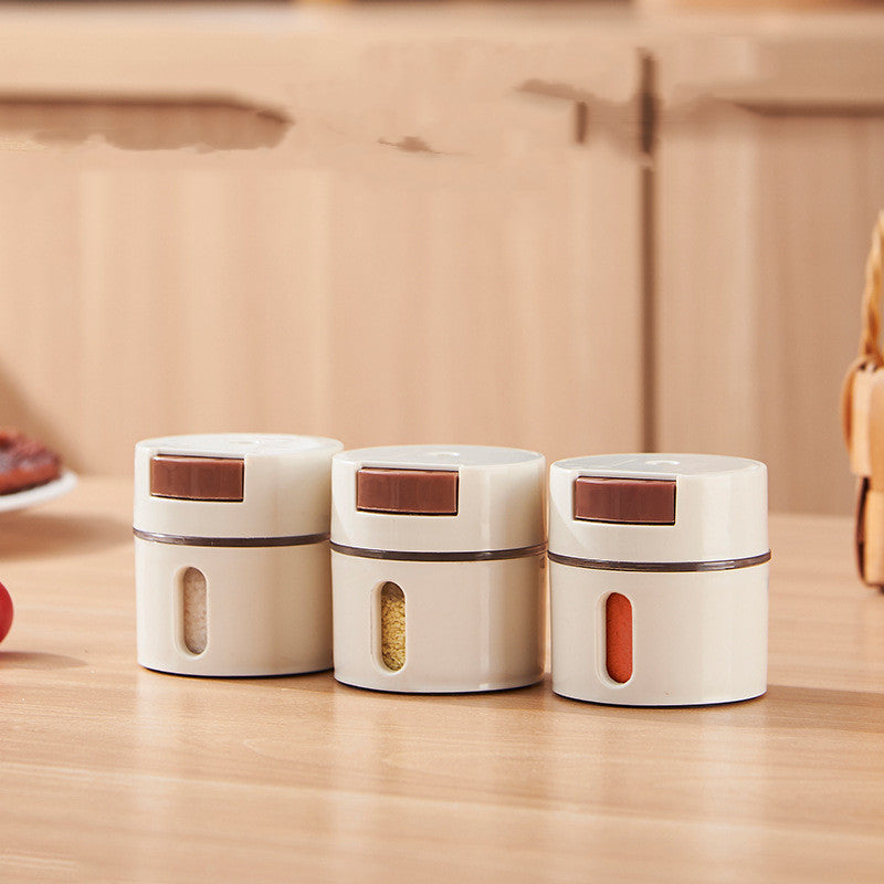 Three seasoning canisters on a kitchen counter with salt, sugar, and chili flakes visible through the window